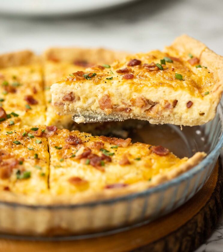 Quiche Lorraine side shot lifting slice of quiche lorraine out of pie dish
