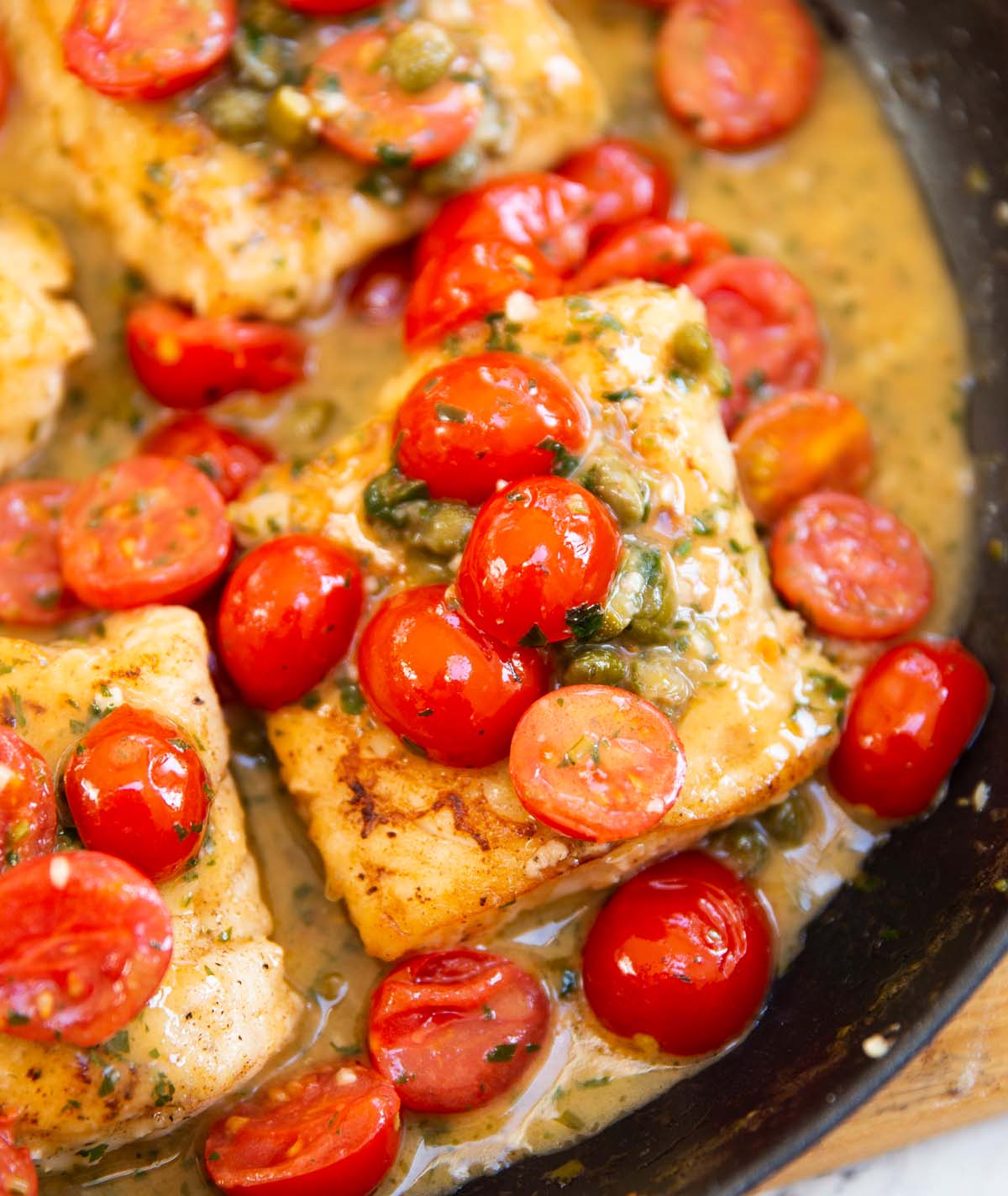 cod with capers and tomatoes in large pan
