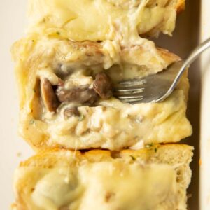 close up shot of silver fork digging into cheesy chicken mushroom slider